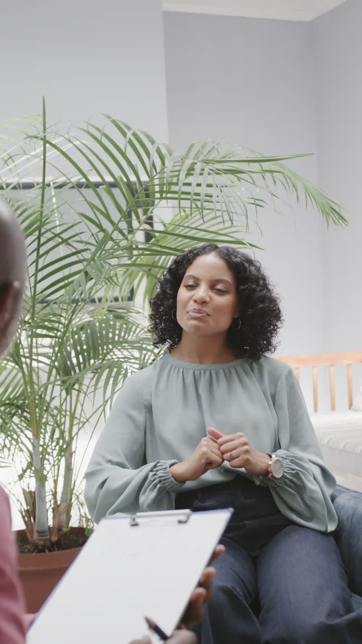 Vertical video of diverse male therapist and female patient talking during therapy, slow motion