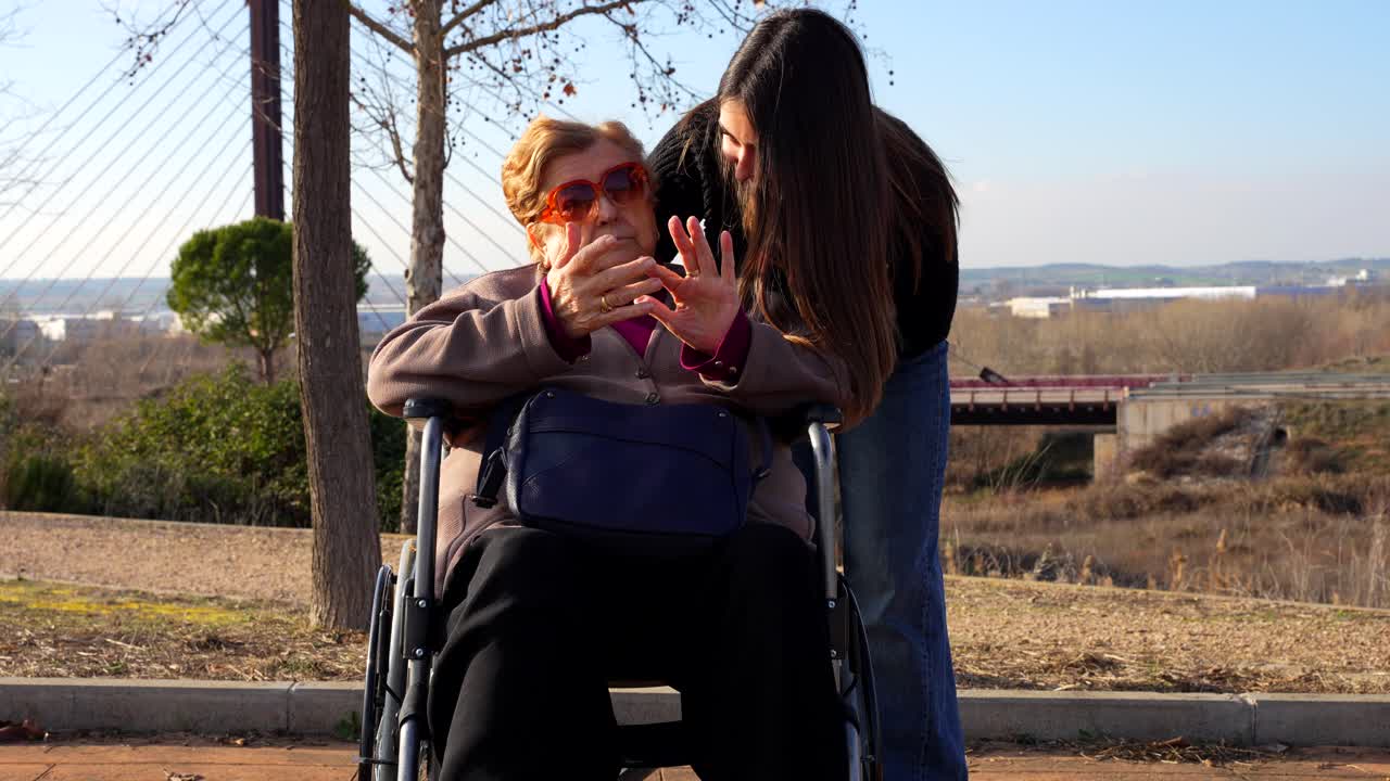 Wheelchair-bound grandmother counting with fingers beside her granddaughter
