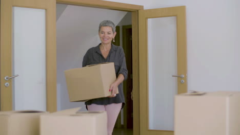 feliz hermosa mujer madura entrando en una nueva casa con cajas de cartón