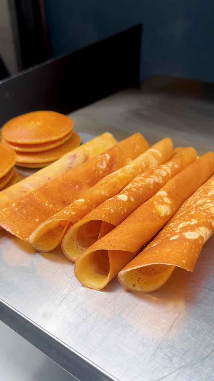 Close-up camilan jajanan kaki lima Khanom Tokyo yang baru dibuat di permukaan logam di Bangkok.