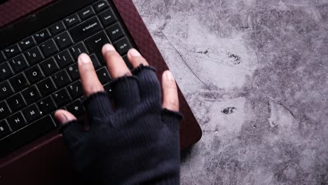 hand in gloves typing on a laptop keyboard