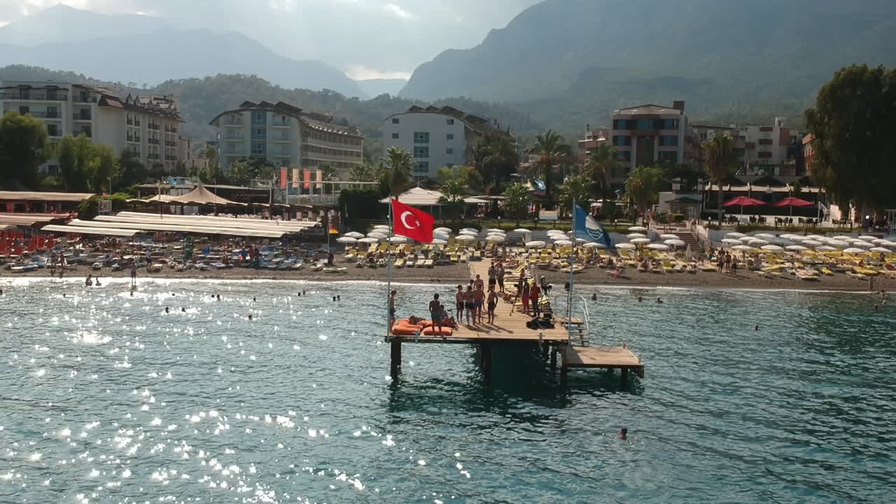 Ripresa aerea con drone di persone che nuotano e prendono il sole su un molo in una spiaggia di hotel a Kemer, Turchia.