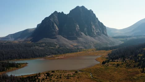 stunning aerial drone landscape nature tilting up shot of a large meadow with a small stream revealing the large and beautiful lower red castle lake in the high uinta national forest in utah