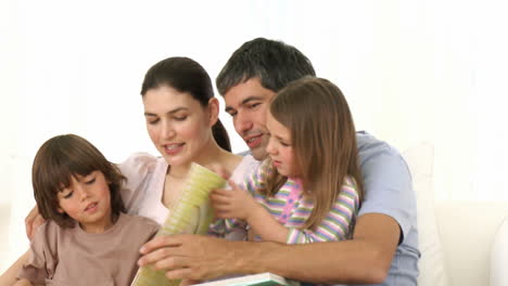 Familia-Sentada-En-El-Sofá-Leyendo-Un-Libro-Juntos