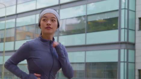 Close-Up-Side-View-Of-Young-Woman-Exercising-Running-Along-City-Street-Wearing-Wireless-Earbuds-1