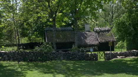 bolsestugan cottage surrounded by lush deciduous trees and stone fence in halland, sweden