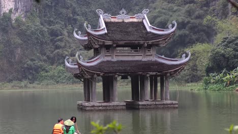 tourists row boat near traditional pavilion