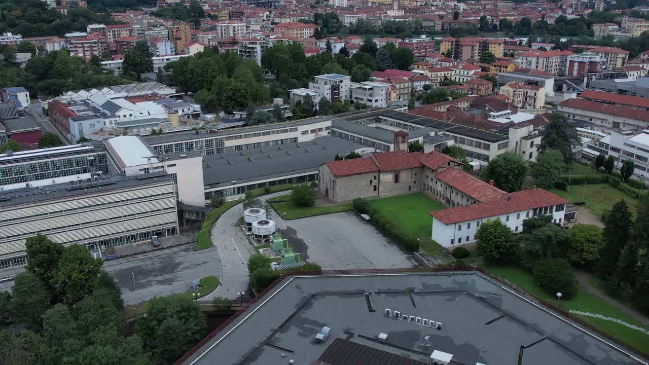 Unesco-listed Olivetti district buildings in Ivrea's framed by the Alps and Mount Mombarone in the background, drone shot, slow motion, sunny and cloudy skym, Piedmont, Italy