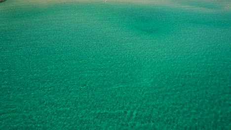 revelación aérea cinematográfica de la playa del paraíso con agua turquesa, rodeada de vegetación verde y altos picos montañosos, isla de thassos, grecia, europa