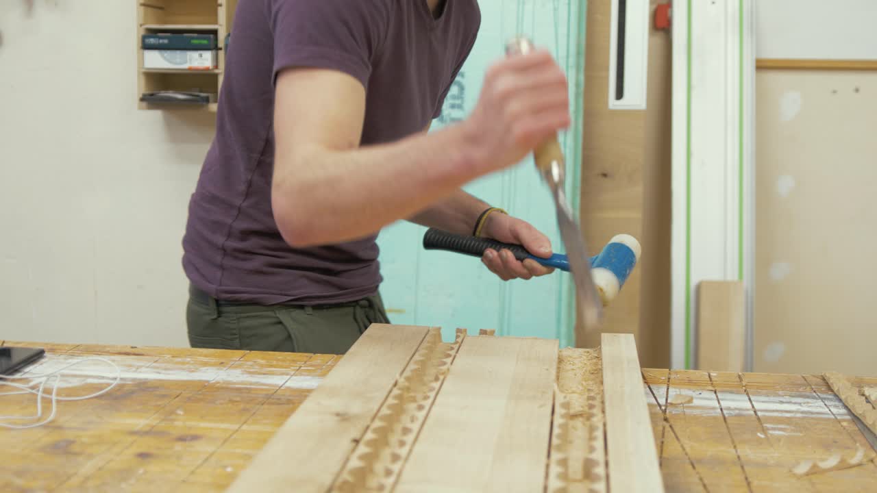Young male carpenter chiseling recess in oak timber