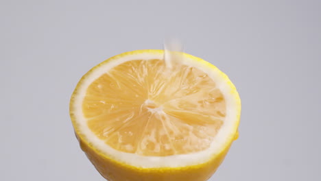 slow motion macro shot of flowing water from lemon slice on white background