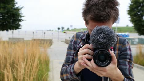 handsome young man holds camera getting ready to