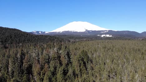 a drone shot flying twoards mount saint helens in washington, an aerial shot of a snowy mountain in the pacific northwest