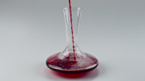 primer plano vertiendo un cuenco de vidrio de vino rojo en el interior. decantador de llenado de líquido alcohólico