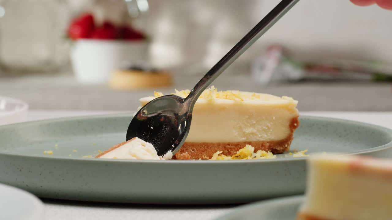 A slice of lemon cheesecake being eaten with a spoon