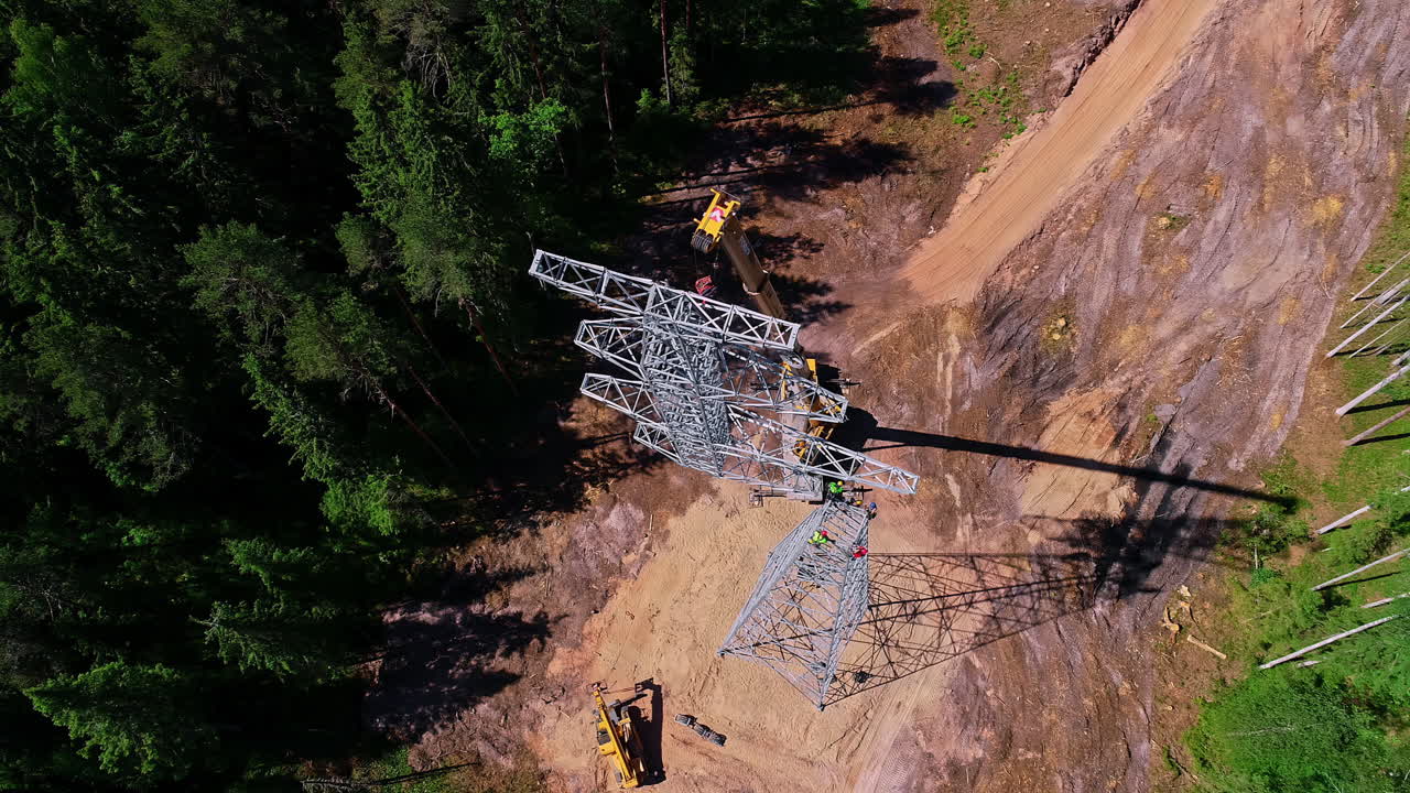 Top shot of workers operating a large crane to install an electric pole on a bright sunny day