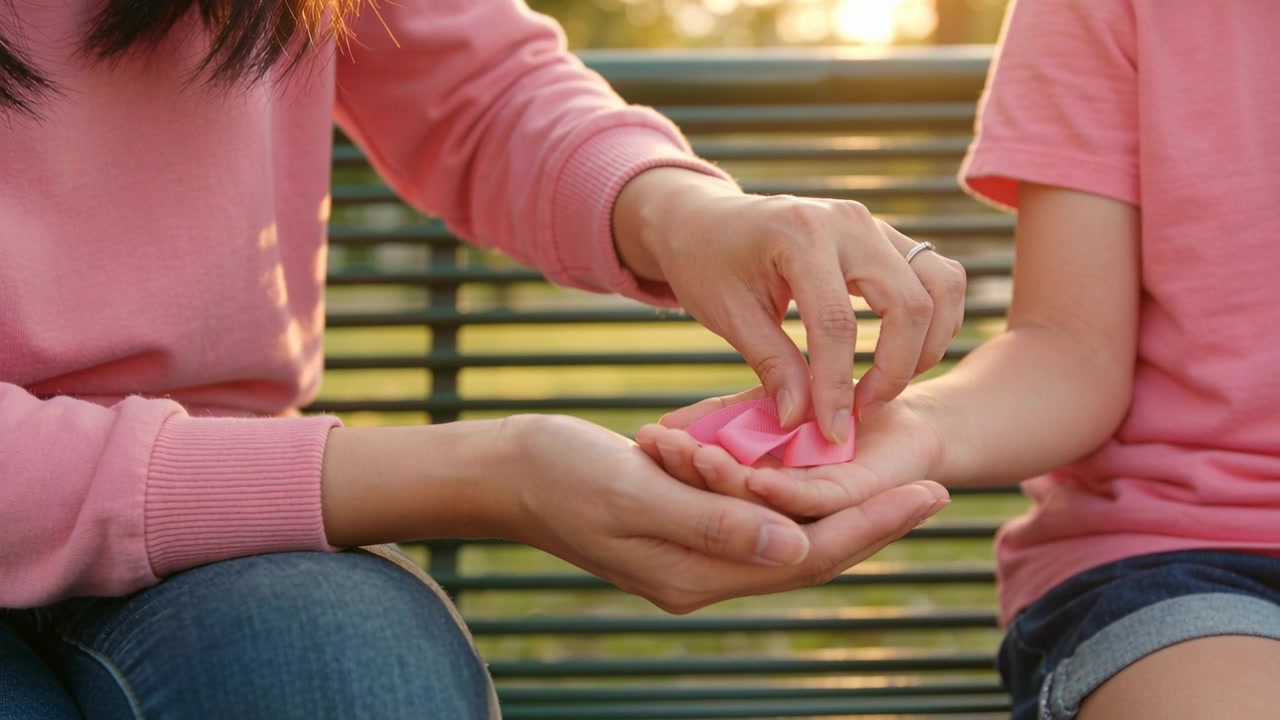 Madre e hijo sosteniendo un lazo rosa de concienciación sobre el cáncer