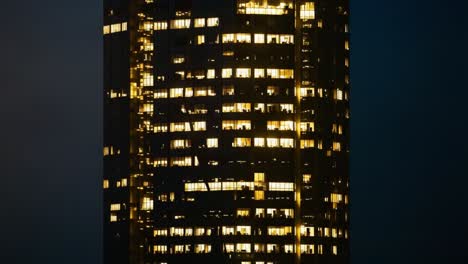 illuminated windows of a tall city skyscraper at night