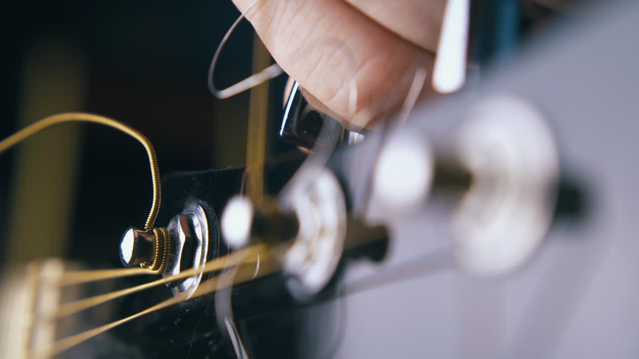 기타리스트는 어쿠스틱 기타에서 여섯 번째 메탈 베이스 스트링을 조율합니다.