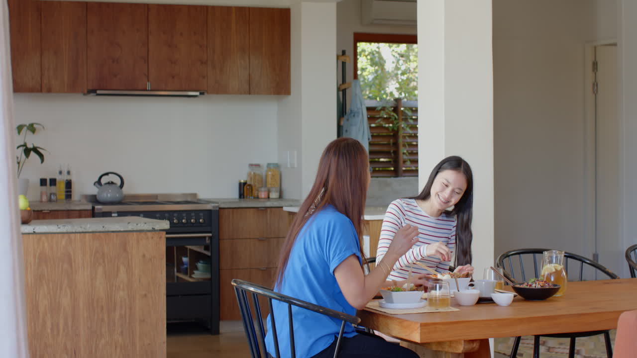 Eating breakfast together, asian mother and daughter enjoying meal at kitchen table