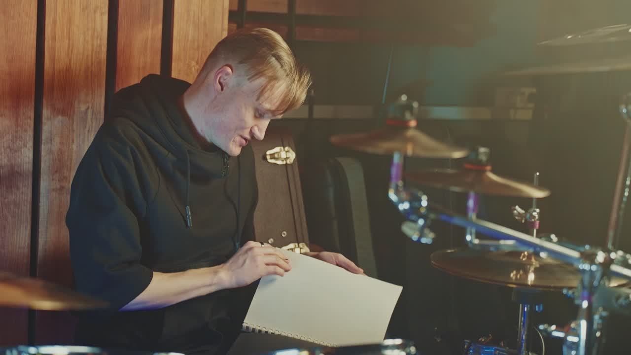 Drummer Studying Sheet Music in Recording Studio