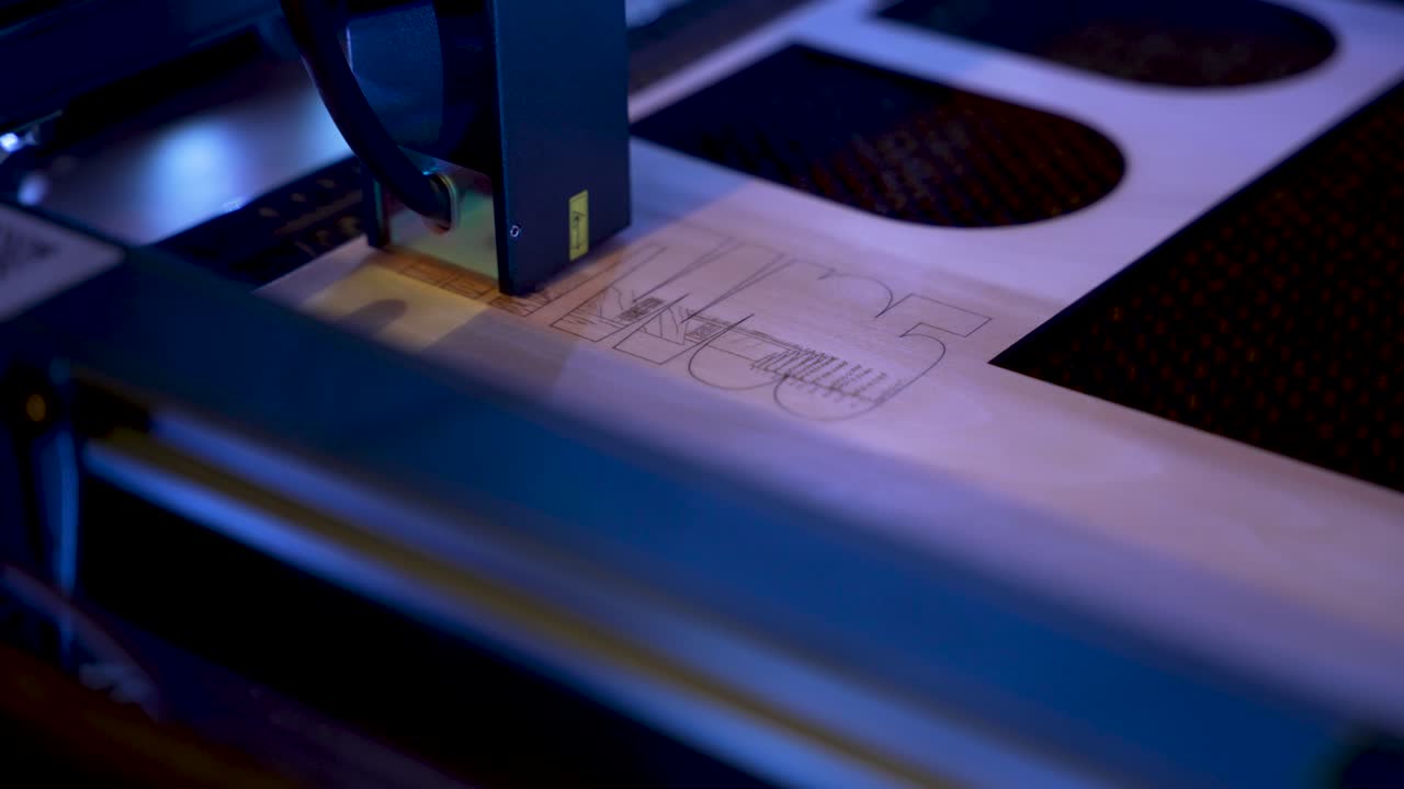 Close up view of a blue laser engraver engraving wood, emitting a purple glow on the surface