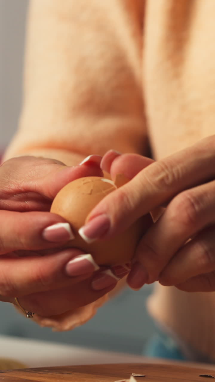 Hands crack brown egg peeling shell, preparing eggs for decoration, vertical