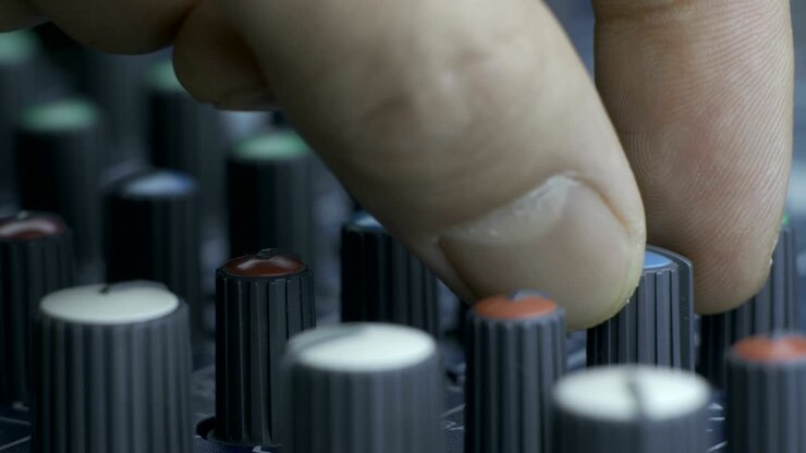 Dita maschili che girano le manopole dell'equalizzatore su un mixer