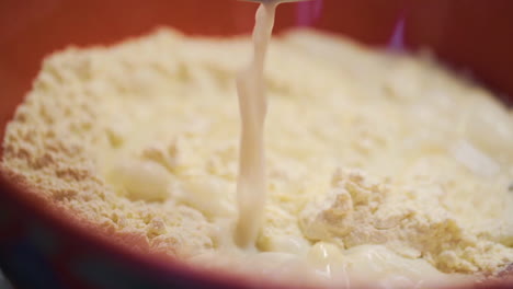 pouring a cup of milk into a bowl of flour in slow motion