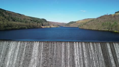 Aerial-descending-view-of-water-cascading-over-the-Derwent-Dam,-home-of-the-Dam-Busters-practice-during-the-second-world-war