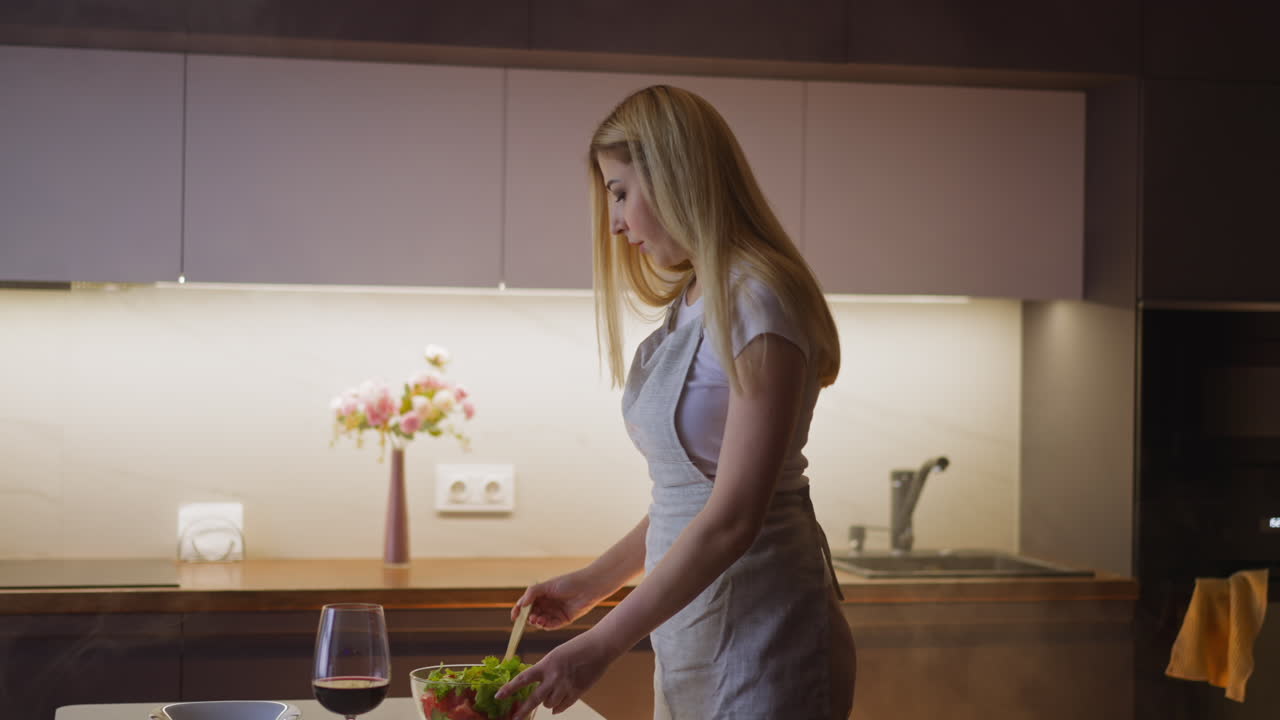 Una donna mescola un'insalata di verdure fresche per cena a tavola.