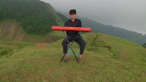 young musician male playing piano alone in remote hills of southeast asia