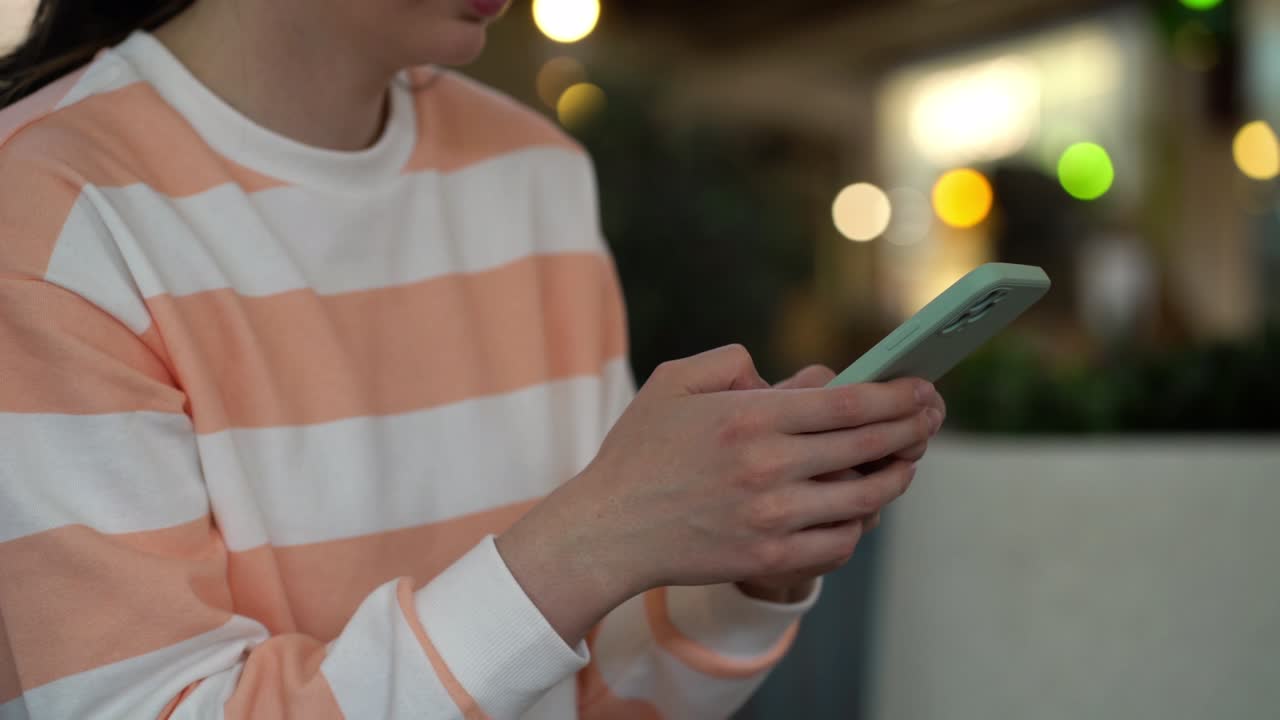 centrarse en la mano femenina usando el teléfono inteligente y publicando en las redes sociales.