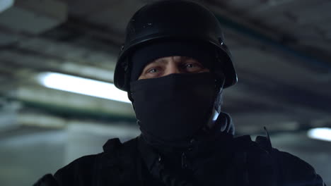 swat member standing in dark building. masked military soldier posing at camera