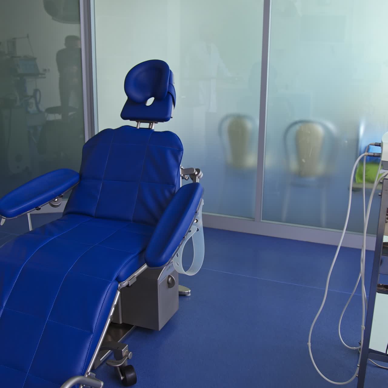 Blue comfortable folding chair in dentist's cabinet. Light room with diverse equipment for stomatological purposes