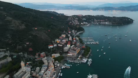 aerial view of portovenere village in italy surrounded by buildings and sea with boats parked at the post and ships sailing in the water during evening