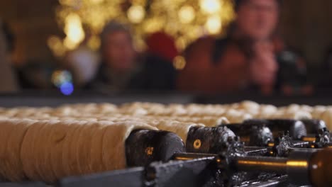 Rolling-Trdelnik-Closeup-Y-Gente-En-Navidad-Praga,-Comida-Callejera-Tradicional-De-La-República-Checa