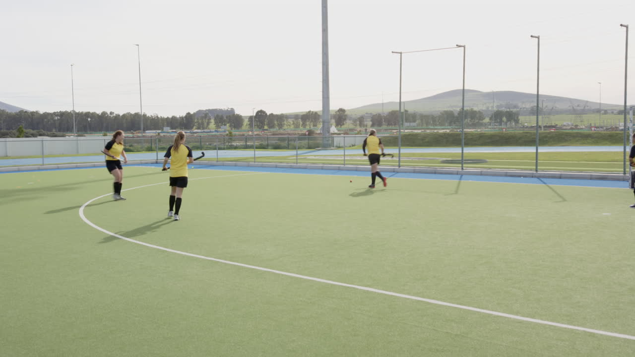 Female hockey players practicing on field, focusing on teamwork and strategy