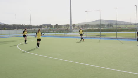 female hockey players practicing on field, focusing on teamwork and strategy