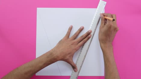 tracing diagonal lines with ruler and pencil on paper, pink background.