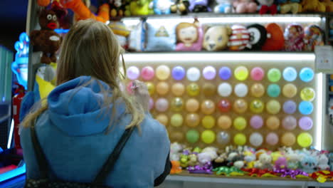 woman popping a balloon with a dart in amusement park