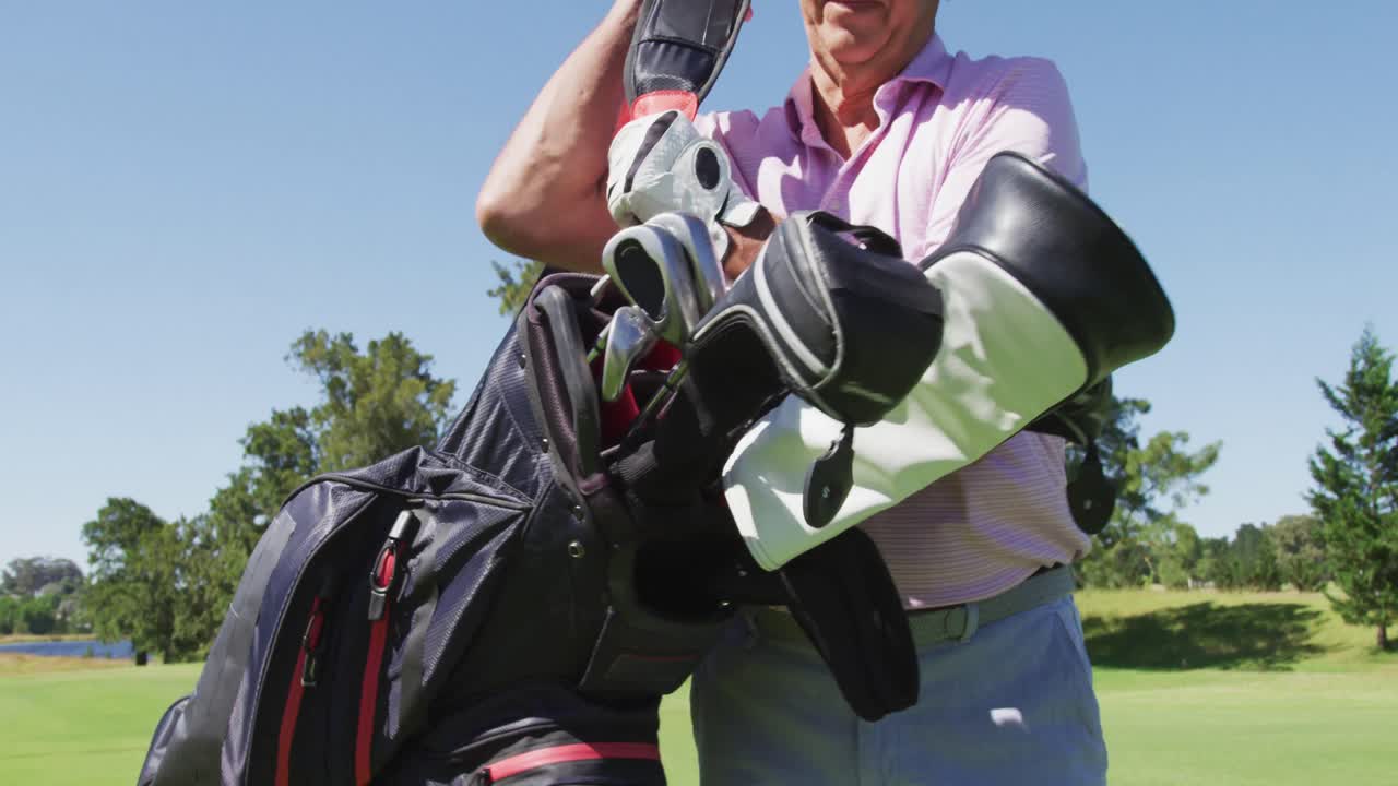 밝은  ⁇ 은 날에 골프 코스에서 골프 가방을 들고  ⁇ 고 있는 백인 노인