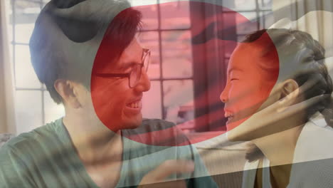 animation of flag of japan over asian father with daughter embracing at home