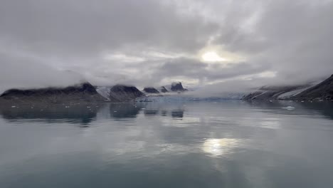 Panning-of-a-landscape-in-a-glacier-reflecting-in-the-water-in-the-Arctic-Sea-along-the-northern-coast-of-Svalbard-during-an-expedition-cruise-on-a-cloudy-day