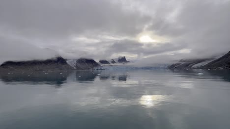 panning of a landscape in a glacier reflecting in the water in the arctic sea along the northern coast of svalbard during an expedition cruise on a cloudy day