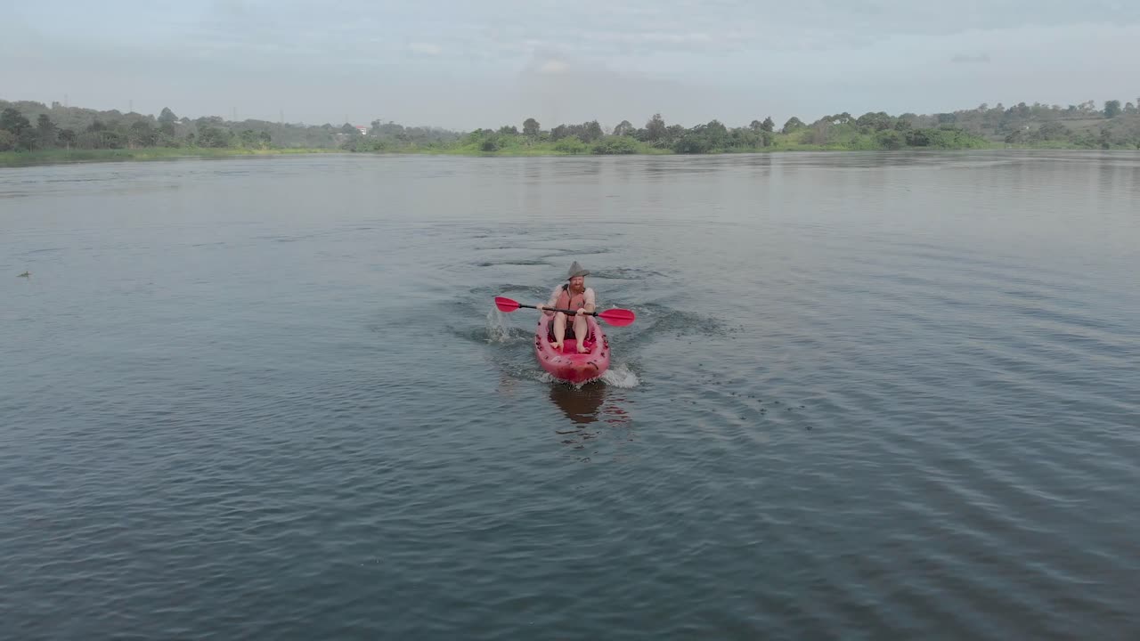 나일강에서 노를 젓는 빨간 카약을 타고 앞에서 모험을 즐기는 백인을 추적하는 공중 촬영