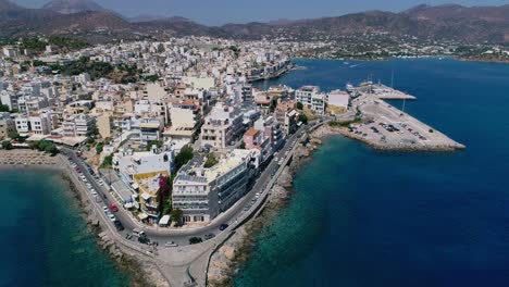 Drone-shot-over-the-marina,-seaside-boulevard,-beaches,-summer-in-Agios-Nikolaos-Crete-Greece