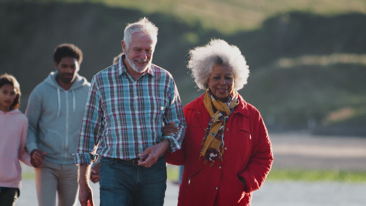familia activa de varias generaciones caminando a lo largo de la costa en vacaciones de playa de invierno