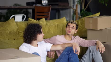 homosexual couple talking in a new apartment around boxes