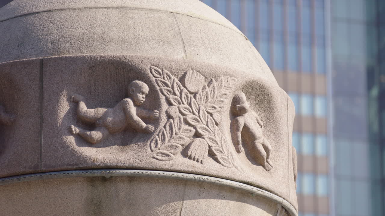 Babies or cherubs carved into the granite base of the Sun and Earth sculpture